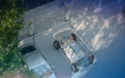 Aerial shot of a car charging at an electric station, with power cables connecting it to the charging unit Aerial shot of a car charging at an electric station, with power cables connecting it to the charging unit